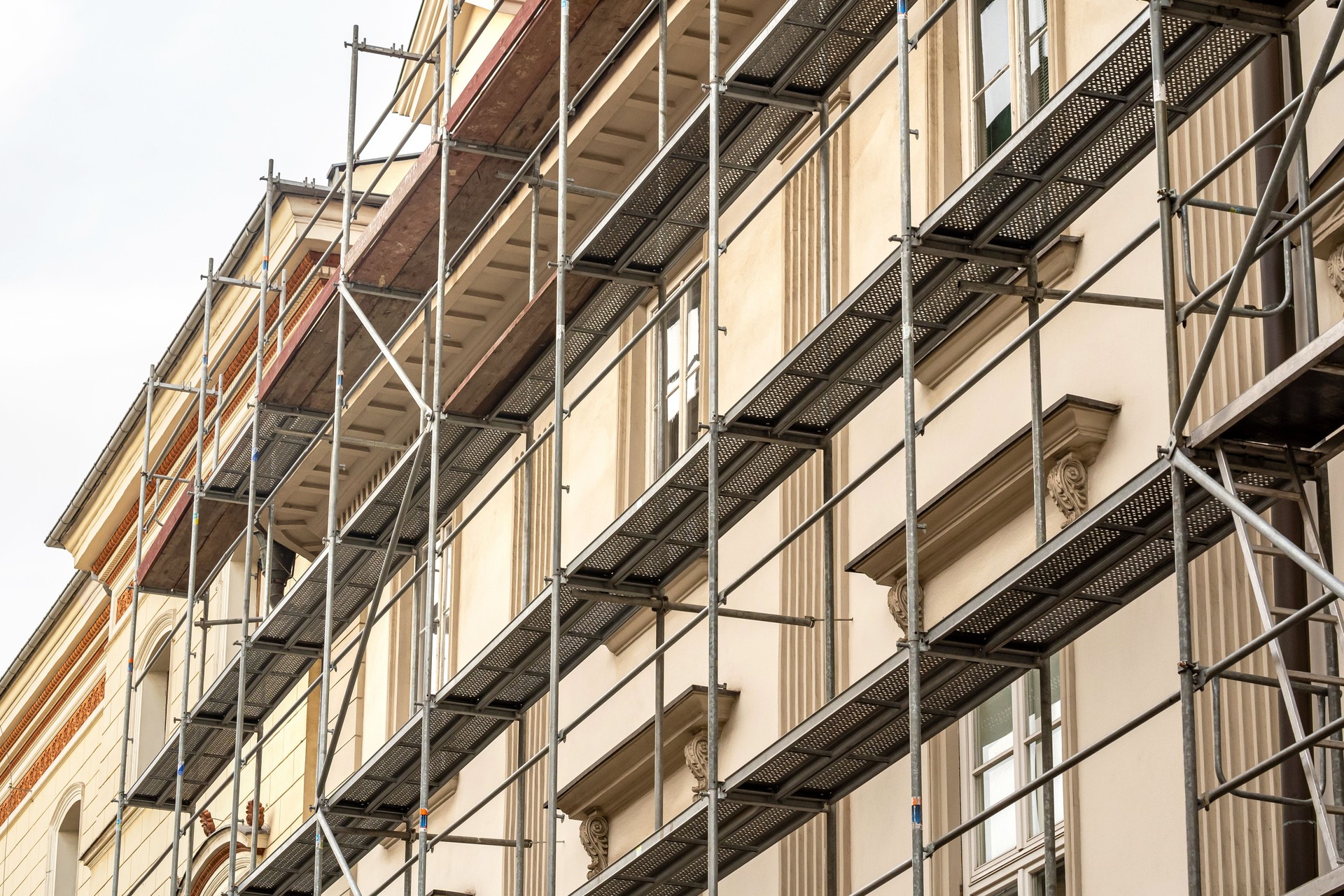 Andamiaje en una antigua casa de vecindad genérica, detalle de fachada de edificio histórico renovado, primer plano, nadie. Industria de la restauración, arquitectura antigua, concepto simple de renovación inmobiliaria, sin personas